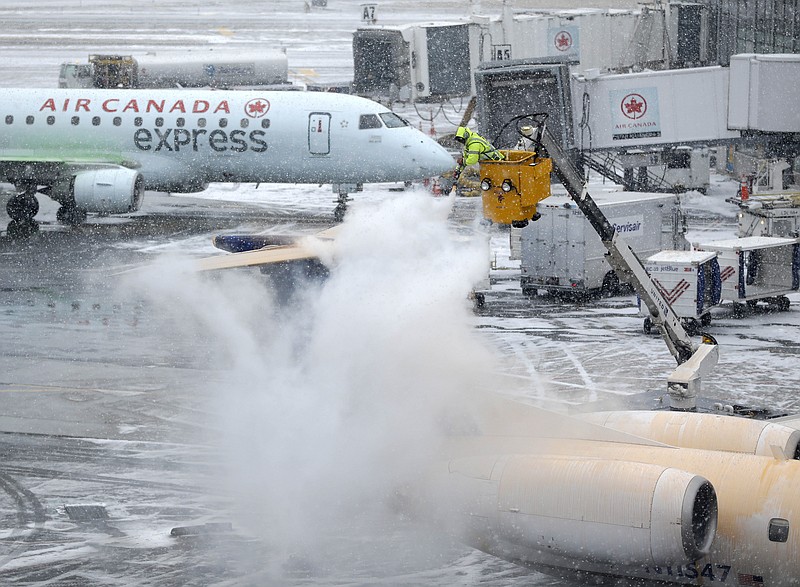 A plane is de-iced during a light snow at LaGuardia Airport in New York, Monday, Jan. 26, 2015. Airlines canceled thousands of flights into and out of East Coast airports as a major snowstorm packing up to three feet of snow barrels down on the region.