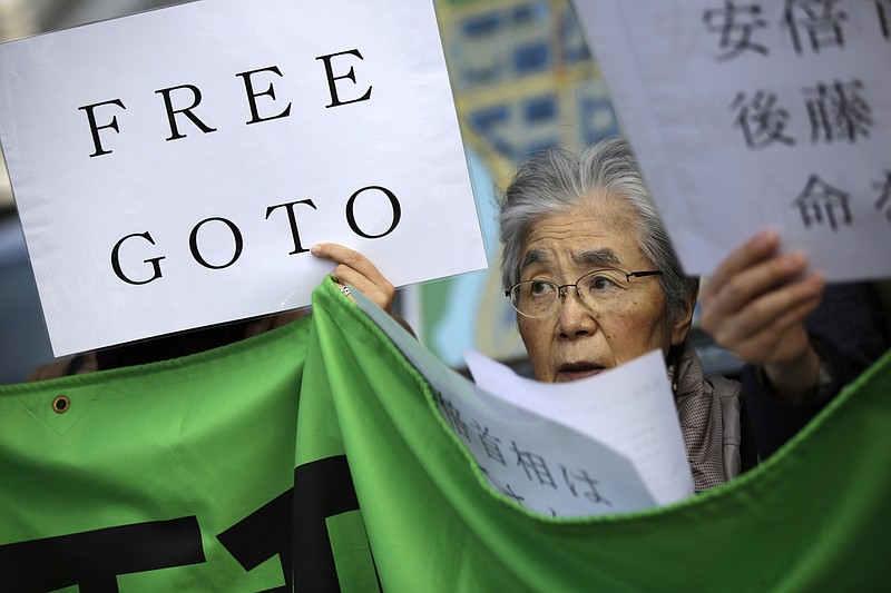 A woman along with other protesters hold a placard and chant "Free Goto" during a rally outside the prime minister's official residence in Tokyo, Tuesday, Jan. 27, 2015. 