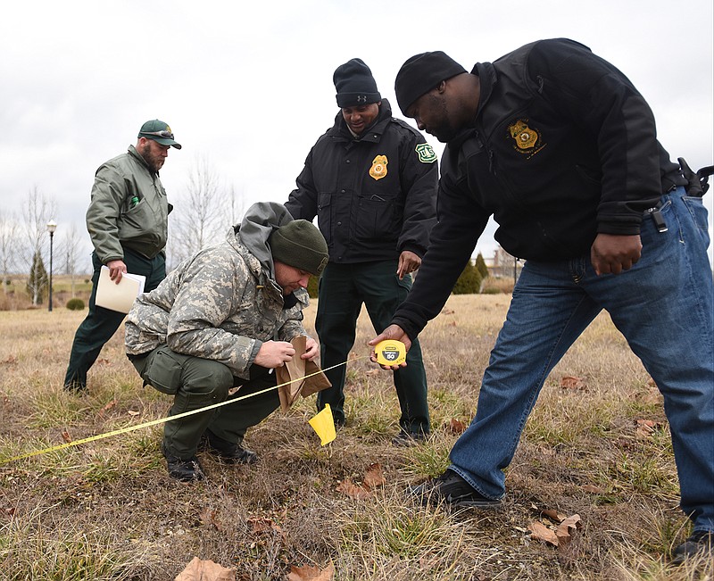 U.S. Forest Service law enforcement officer Duane Crims, front, along with Chris Gordon, left, Bob Foxworth, second from left, and Eric Wiley investigate a mock archaeological site Tuesday near the Embassy Suites during training exercises.
