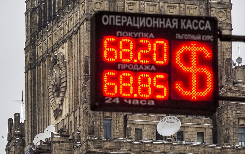 
              A sign at an exchange office with headquarters building of the Ministry of Foreign Affairs of the Russian Federation with the Soviet Sign in the background in Moscow, Russia, Thursday, Jan. 29, 2015. The Russian ruble extended its losses on Thursday, declining by 1.5 percent to 69 rubles against the dollar. (AP Photo/Alexander Zemlianichenko)
            