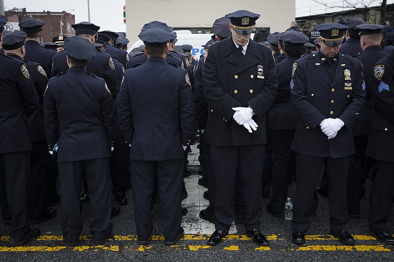 
              FILE - In this Jan. 4, 2015 file photo, some police officers, left, turn their backs in a sign of disapproval as Mayor Bill de Blasio remaks are transmitted on a large video screen during the funeral of New York Police Department Officer Wenjian Liu outside of a funeral home in the Brooklyn borough of New York. Mayor Bill de Blasio declares he has moved past the crisis with police that threatened to derail his administration. He says in an interview with The Associated Press that he was able to pull off the feat sticking to a strategy to maintain the moral high ground and avoid confrontation with police unions. At the same time, public opinion turned against police for their behavior in the feud, including turning their backs on the mayor. (AP Photo/John Minchillo, File)
            