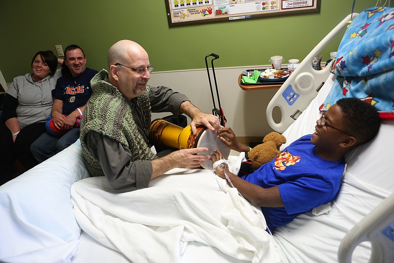 Bob Stagner, Southeast facilitator for The Rhythmic Arts Project, teaches 11-year-old Michael Wiren how to play the djembe while his parents Chris and Andrea Wiren look on at Erlanger Hospital on Jan. 27, 2015. Stagner plays drums with kids at the hospital every Tuesday. 