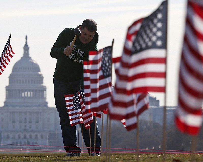 
              FILE - In this March 27, 2014 file photo, with the Capitol in the background, Army veteran David Dickerson of Oklahoma City, Okla., joins others to place 1,892 flags representing veteran and service members who have died by suicide to date in 2014, on the National Mall in Washington.  The Senate is expected to take up a bill Monday named for Clay Hunt, a 26-year-old veteran who killed himself in 2011. The bill is aimed at reducing a suicide epidemic that claims the lives of 22 military veterans every day.  (AP Photo/Charles Dharapak)
            