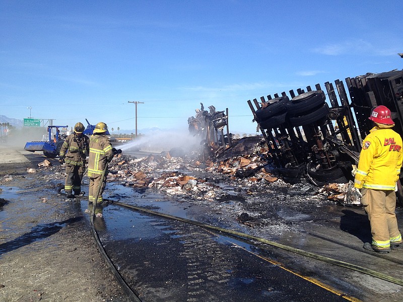 Firefighters respond to a collision involving two semi trucks on westbound Interstate 10 near Coachella, Calif., on Monday, Feb. 2, 2015. One truck spilled thousands of pounds of frozen chicken and the other lost thousands of the bees it carried.