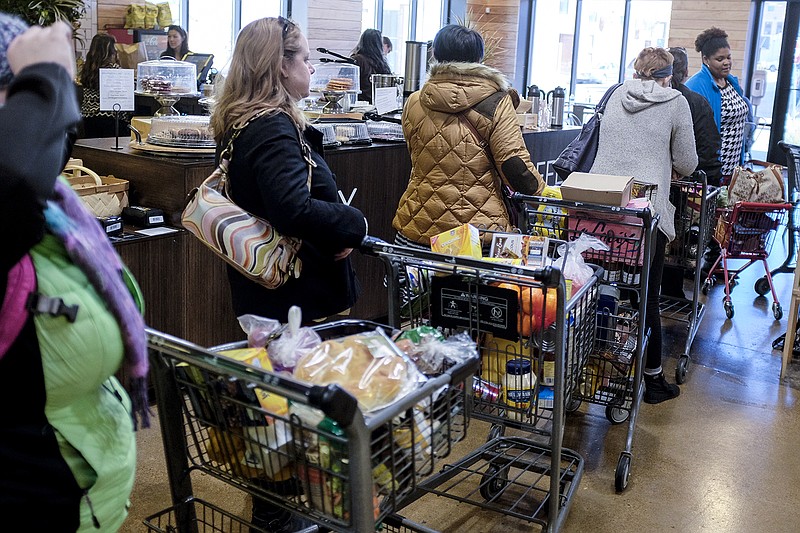 Shoppers wait in line to check out, some of whom said they waited for as long as 45 minutes, during a 50% off sale Thursday, Feb. 5, 2015, at the Grocery Bar, formerly Enzo's Market, on Main Street in Chattanooga.