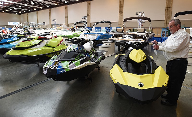 Gerald White, of White's Cycle and Marine, adjusts a price tag on a Sea-Doo at the Chattanooga Boat and Sport Show at the Chattanooga Convention Center. The show continues through Sunday.