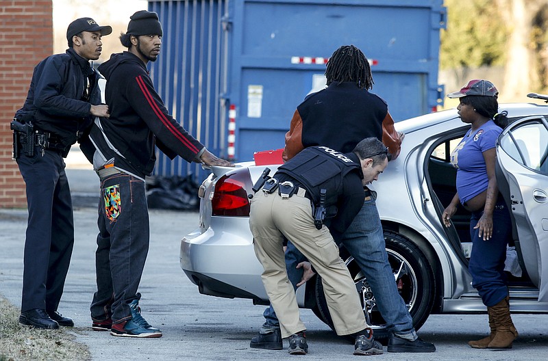 Crime Suppression officer Saint Louis, left, and Chattanooga Housing investigator Pete Galyon, center, search Dalvin Thompson, center right, and Chris Kennemer as Orneasha Swafford, right, watches after the officers stopped them for a traffic violation at the East Lake Courts public housing site Thursday, Feb. 5, 2015, in Chattanooga, Tenn. 