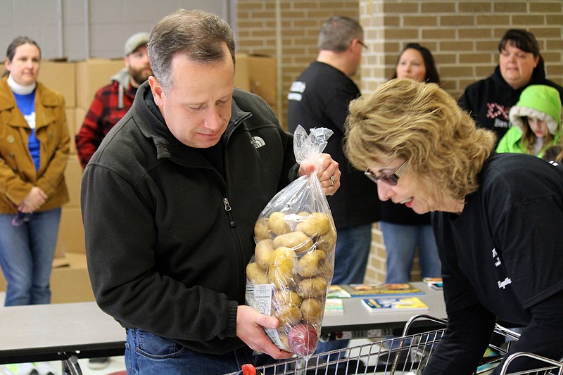 Jeff Deal, a volunteer from Mount Rachel Baptist Church, and another volunteer load potatoes as part of the Raider Nation Mobile Pantry at Southeast Whitfield High School.