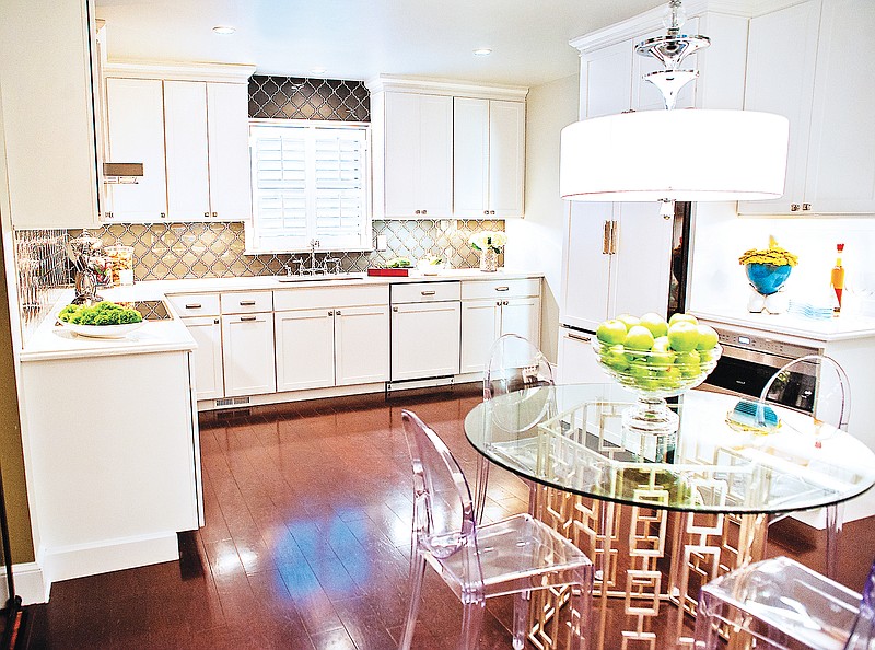 Although only 12 feet wide by 19 feet long, the kitchen in the home of Ahmed Alshabibi and Greg Turner appears much larger due to white maple cabinets that reflect natural lighting and recessed ceiling lighting in the glass-top table. The wide- plank walnut flooring gives a feeling of age that is appropriate for the circa-1920s bungalow.