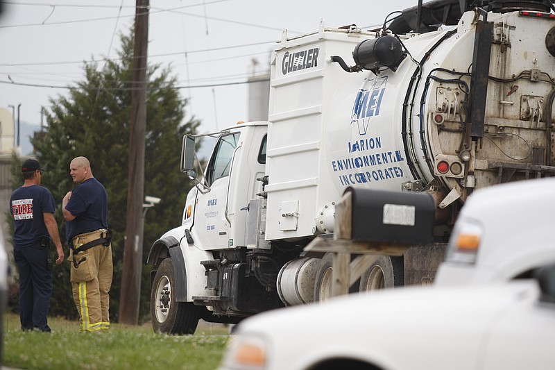 Firefighters stand near a chemical cleaning truck on Callahan Road in Dalton, Ga., after a chemical explosion at MFG Chemical.