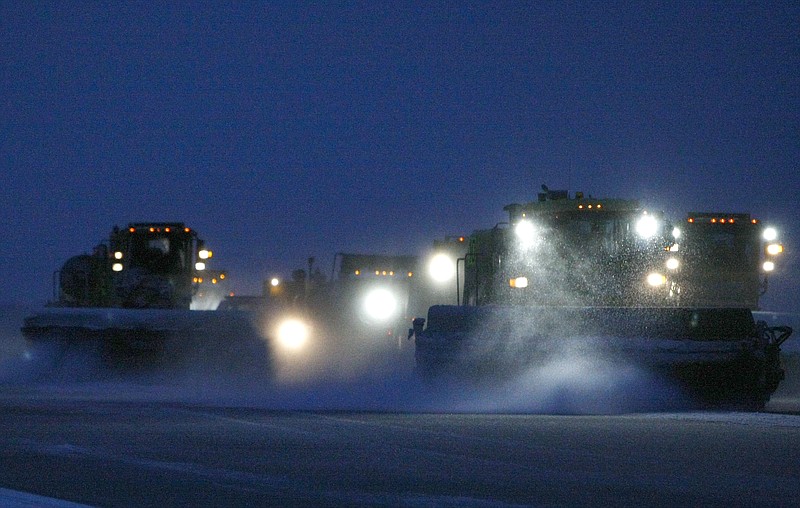 Crews work to keep the runways clear at Memphis International Airport at dawn on Monday, Feb. 16, 2015, in Memphis, Tenn. Thirty-six arrivals and 21 departures were canceled due to the frozen precipitation that began falling overnight. (AP Photo/The Commercial Appeal, Mike Brown)