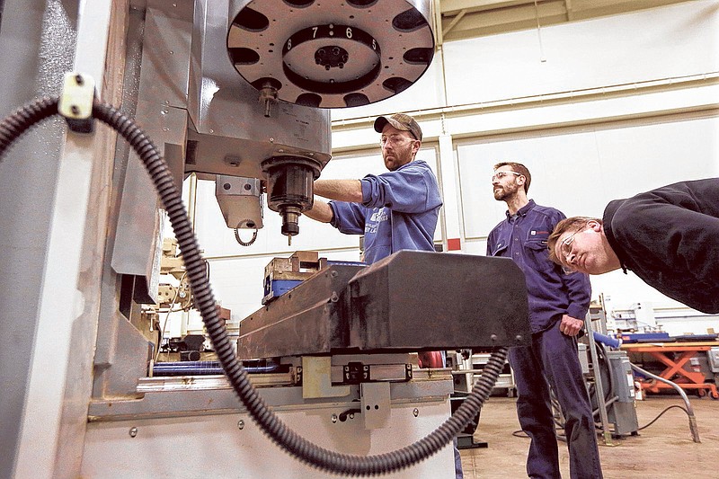 Brad Bancroft, left, operates a mill as Nate Joseph, center, and Adam Woodhams, right, look on in the advanced precision machining class at Lansing Community College, in Lansing, Mich.