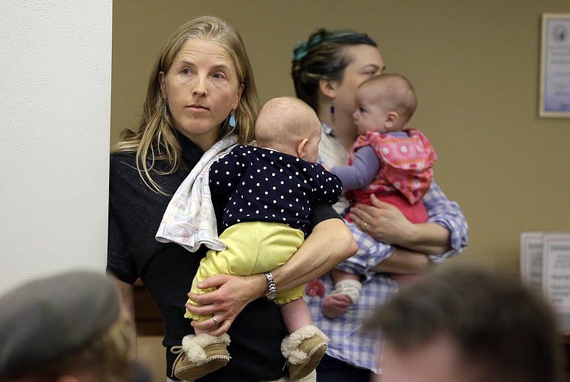 
              Sonja Wright, left, of Ellensburg, Wash., holds her daughter Iris, 4 months, as she waits to testify against House Bill 2009 during a hearing at the Capitol in Olympia, Wash., Tuesday, Feb. 17, 2015. The bill would remove personal or philosophical opposition as an acceptable reason for parents to not vaccinate their school-age children. Currently, Washington allows school vaccination exemptions for medical, religious and personal or philosophical beliefs. (AP Photo/Ted S. Warren)
            