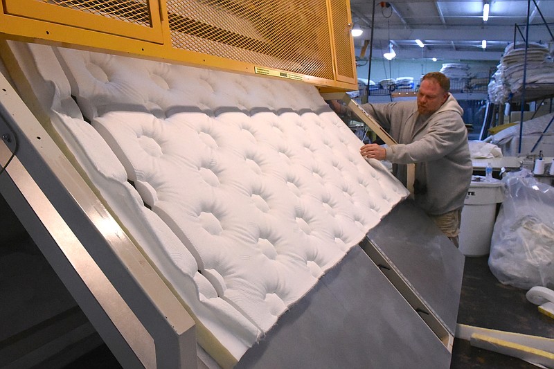 Tim Keller removes a panel of material cut to size as he operates a quilting machine, combining layers of material in the manufacture of a mattress at the MurMaid Mattress Factory and Showroom on Wednesday, Jan. 15, 2015, in Cleveland, Tenn.