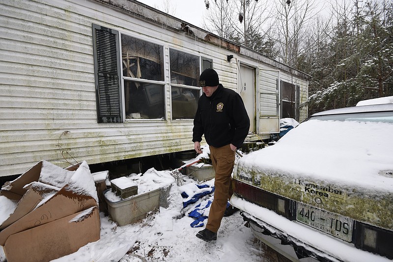 Sequatchie County Detective Chris Walker walks past the front of the house trailer where Bradley Sutter was found dead Wednesday in sub-freezing weather. Sutter allegedly died from exposure.