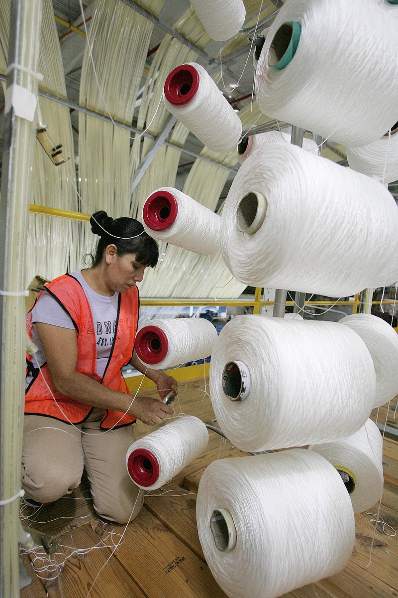 Yeneira Pacheco loads a creelers with yarn at a Mohawk Industries rug manufacturing plant in Calhoun, Ga., in this file photo.