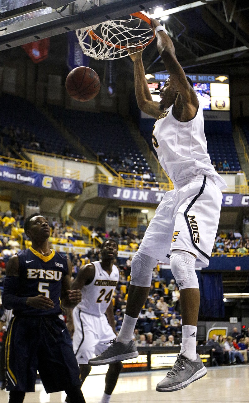 UTC forward Justin Tuoyo, right, dunks over ETSU's Jalen Riley and teammate Casey Jones (24) during the Mocs' Senior Night SoCon basketball game against the ETSU Buccaneers on Feb. 21, 2015, at McKenzie Arena.