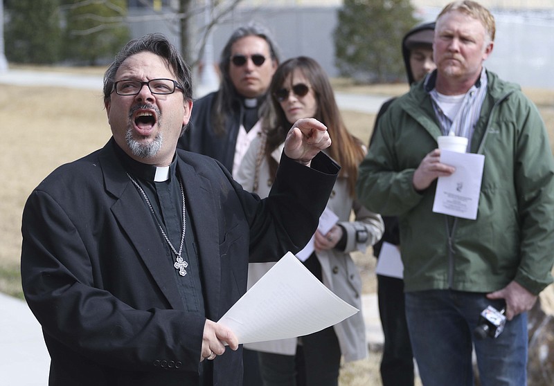 Reverend Brian Merritt leads members of the Mercy Junction Ministry in a protest for the uninsured while staged in The Main Terrain city park adjacent to the Hamilton County Pachyderm Club's luncheon on Monday, February 23, 2015.