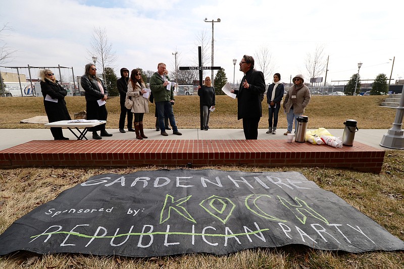 Members of the Mercy Junction Ministry lead a prayer circle for the uninsured before protesting against Sen. Todd Gardenhire while staged in The Main Terrain city park adjacent to the Hamilton County Pachyderm Club's luncheon.