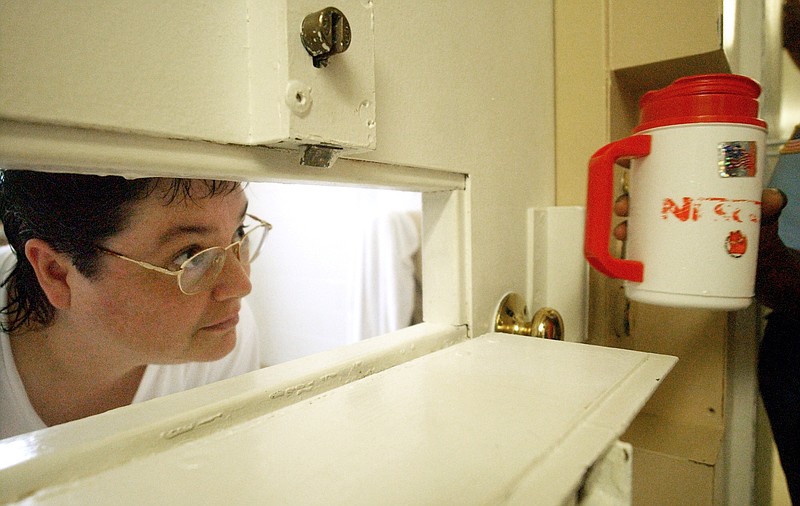In this Tuesday, July 6, 2004, file photo, Kelly Gissendaner, the only woman on Georgia's death row, peers through the slot in her cell door as a guard brings her a cup of ice at Metro State Prison in Atlanta. Gissendaner, 46, is scheduled to be executed Wednesday, Feb. 25, 2015, at the state prison in Jackson. She was convicted of murder in the 1997 slaying of her husband, Douglas Gissendaner. 