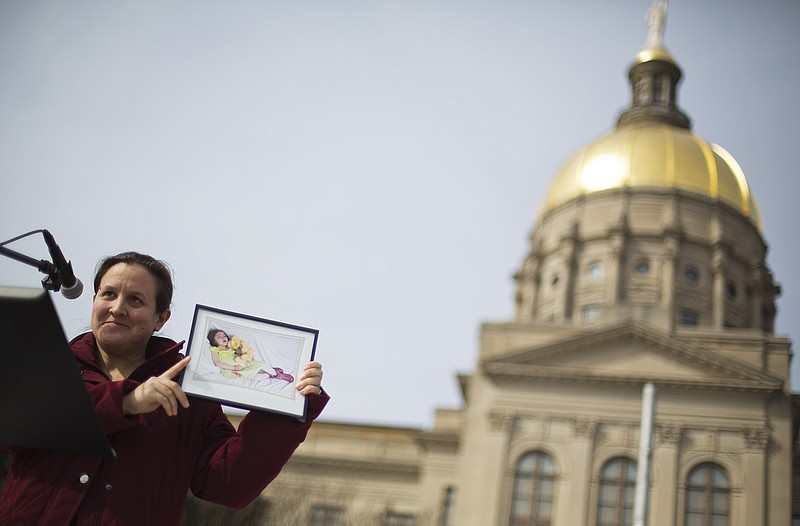 Carrie Hall, of Atlanta, holds up a photo of her daughter Lela, 7, who suffered seizures while living with Dravet Syndrome before passing away Jan. 14 of pneumonia, as she speaks at a rally in front of the Statehouse in favor of House Bill 1, which would legalize possession of cannabis oil for treatment of certain illnesses, Tuesday, Feb. 3, 2015, in Atlanta.