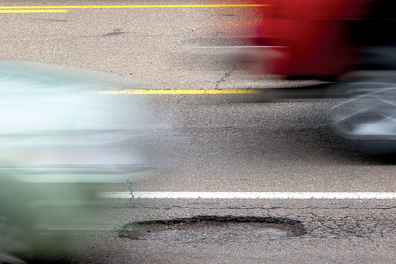Vehicles travel past a newly formed pot-hole on U.S. Highway 153 in Chattanooga.