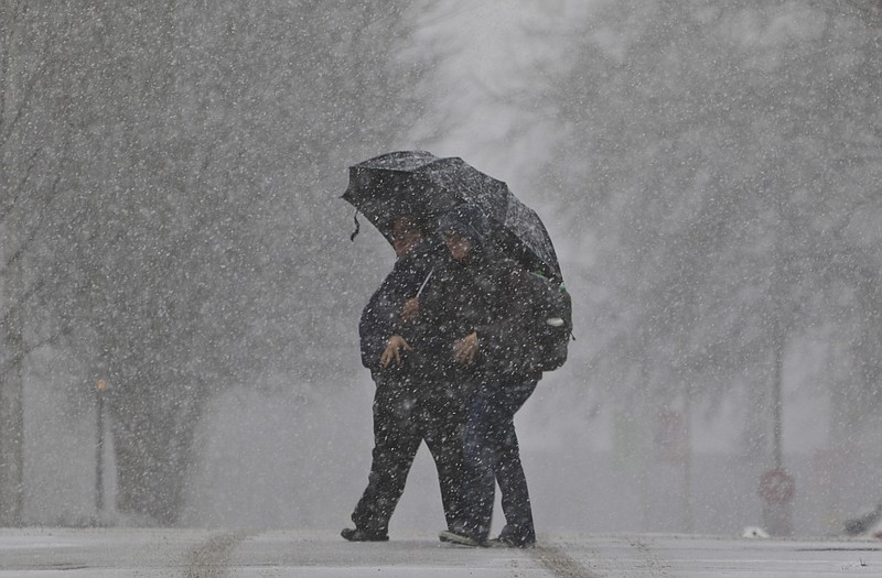 Halina Kuchma and her sister Christina Kuchma cross Lookout Street as snow begins to fall in the Tennessee Valley on Wednesday, February 25, 2015.