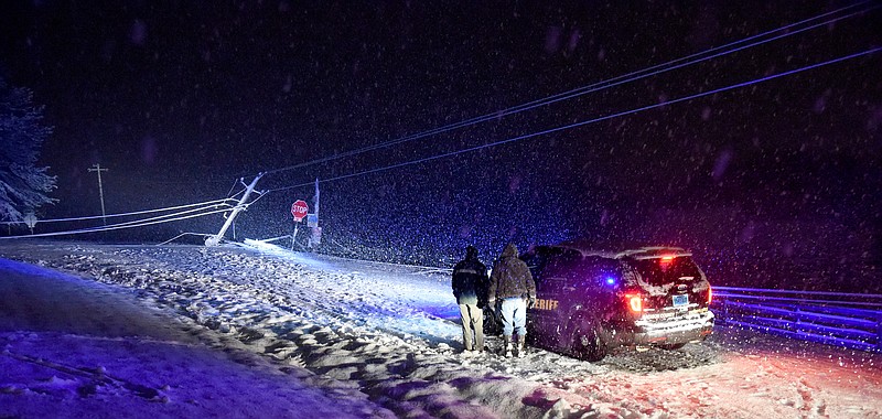 Madison County Sheriff's deputies and Alabama State Troopers look at a fallen power line in northeast Madison County Wednesday night, Feb. 25, 2015 near Huntsville, Ala. Roads crusted with icy slush left over from as much as a foot of snow made travel dangerous across north Alabama early Thursday, but forecasters said temperatures should rise enough to melt away many of the problems. (AP Photo/AL.com, Eric Schultz)