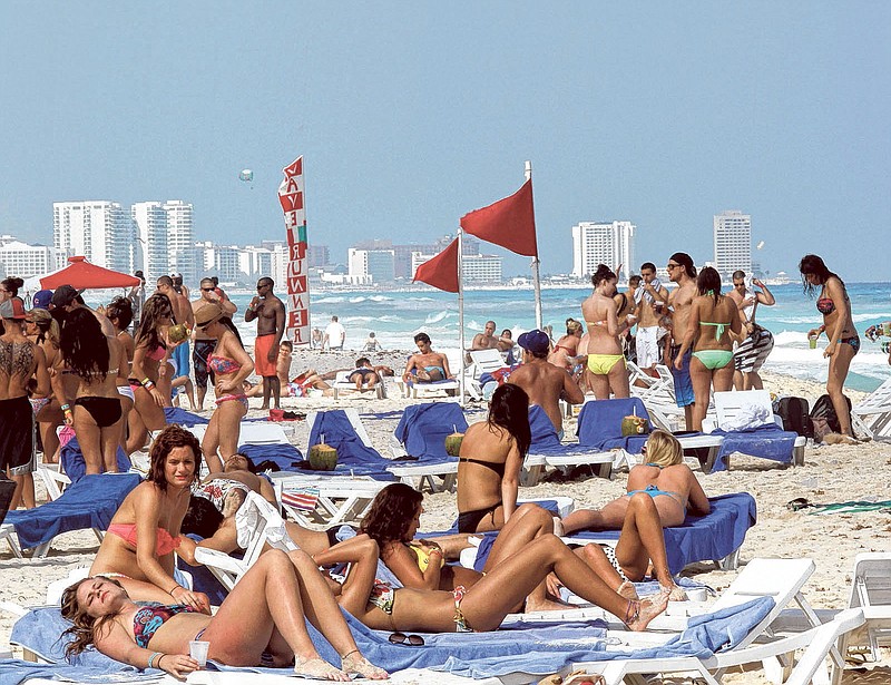 People hang out on the beach during spring break in Cancun, Mexico. The beach resort remains a top destination this year for American spring-breakers seeking an escape from winter.