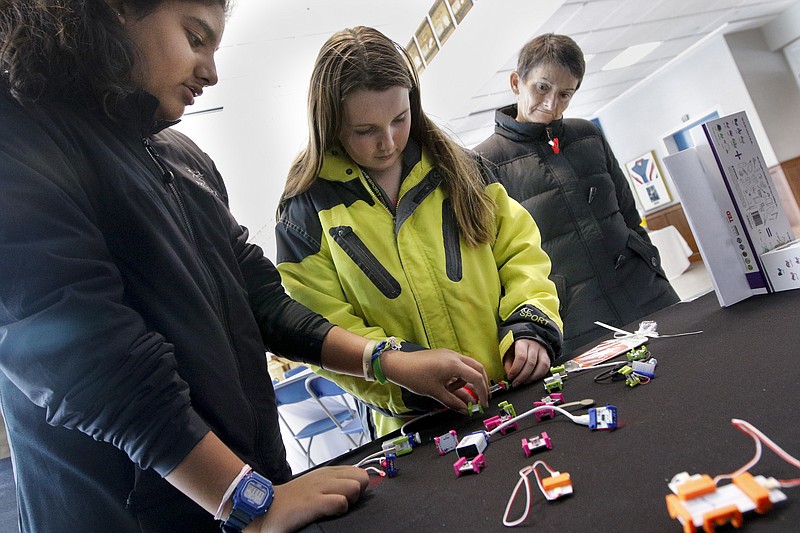 Madeleine Flynn, center, and Shalizeh Rizvi, left, are watched by Muriel Doherty as they put together connections designed to teach the basics of circuitry at a booth at the Mad, Bad, and Dangerous event at Girls' Preparatory School on Saturday, Feb. 28, 2015, in Chattanooga. 