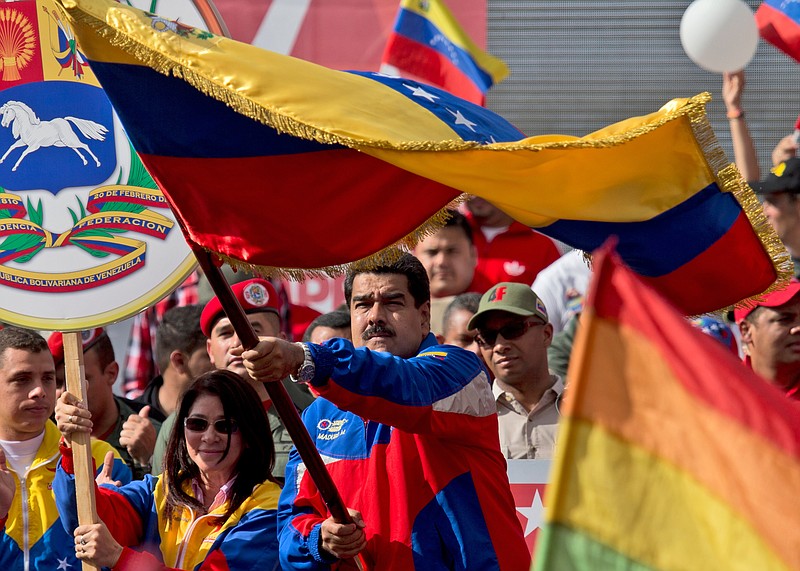 
              Venezuela's President Nicolas Maduro, center, waves a national flag during a rally in Caracas, Venezuela, Saturday, Feb. 28, 2015. Venezuelans took to the streets of Caracas in dueling demonstrations on Saturday, with one group calling attention to a crackdown on opponents of the government and another showing support for the embattled socialist administration. At left is Venezuela's first lady Cilia Flores. (AP Photo/Fernando Llano)
            