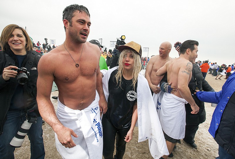 Actor Taylor Kinney, second left, and his fiancée, pop star Lady Gaga, center, along with "Chicago Fire" cast take part in the Chicago Polar Plunge on Sunday, March 1, 2015 in Chicago.