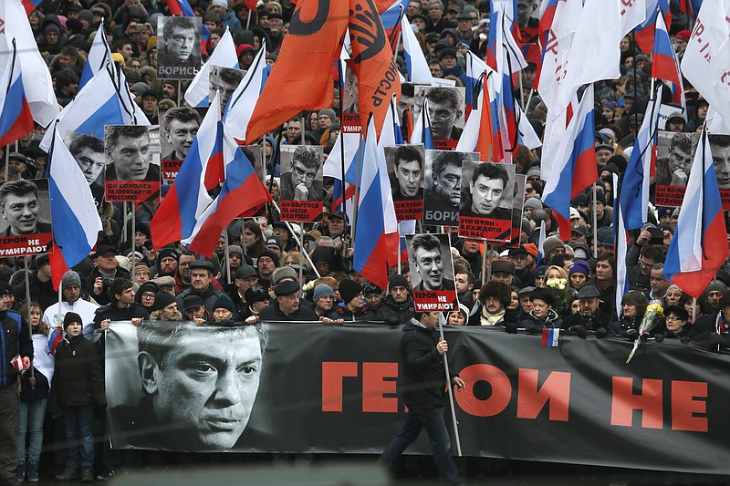 People carry a huge banner reading 'those bullets for everyone of us, heroes never die!' as they march in memory of opposition leader Boris Nemtsov who was gunned down on Friday, Feb. 27, 2015 near the Kremlin, in Moscow on Sunday, March 1, 2015. 