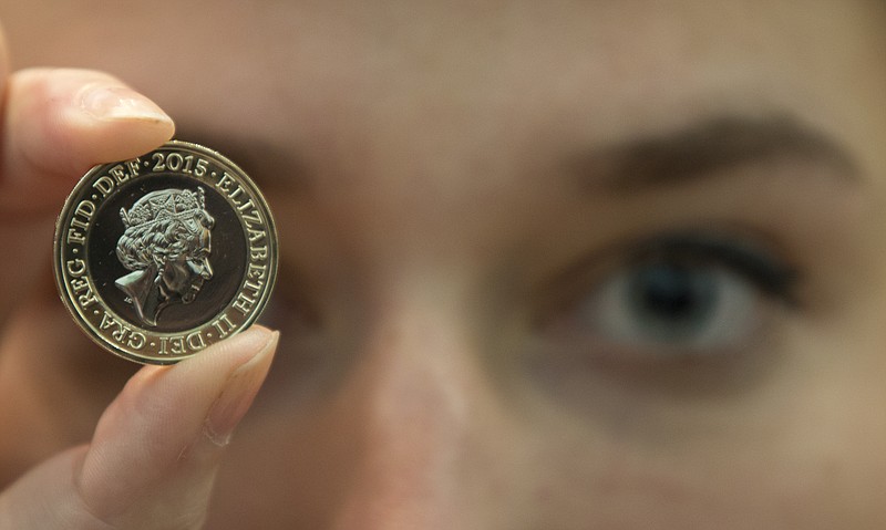 
              A member of the British Royal Mint holds up a new 2 pound coin (US$ 3.08) in front of the new portrait of Britain's Queen Elizabeth II at the National Portrait Gallery in London, March, 2, 2015. The image Britain's Queen Elizabeth II, the fifth of her reign was made by Jody Clark, at 33 the youngest designer. Portraits of the Queen were made in 1952,1968,1985,1998 and 2015, the image will appear on coins later this year.(AP Photo/Alastair Grant)
            