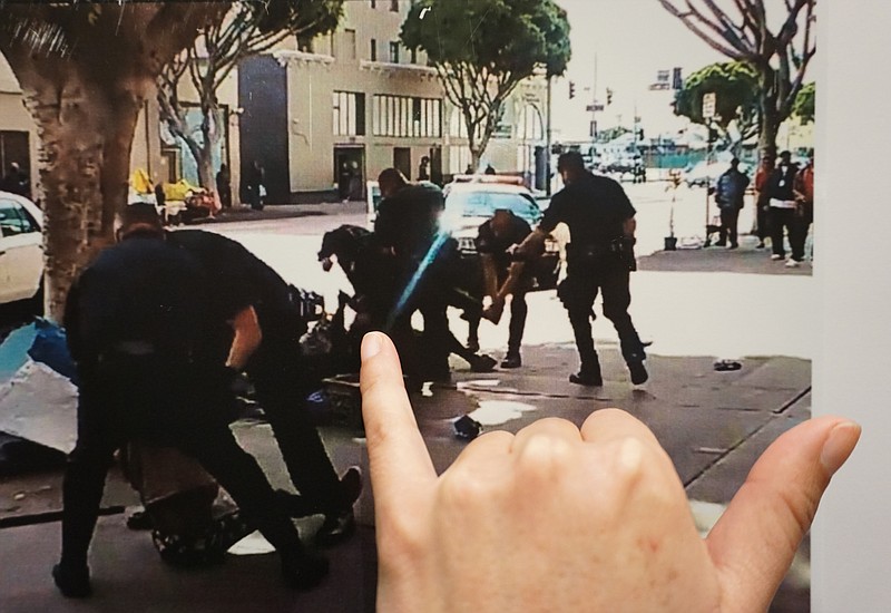 
              Los Angeles Police detective Meghan Aguilar points at photos released by police that could indicate evidence of a suspect holding a police officer's gun, seen in a video grab scene shot by a witness at the scene of the shooting of a homeless man on Skid Row of Los Angeles, displayed at a news conference at police headquarters Monday, March 2, 2015. Chief Charlie Beck says officers fatally shot a homeless man on Skid Row after he grabbed an officer's holster during a struggle. Three Los Angeles police officers shot and killed the man on Sunday, as they wrestled with him on the ground, a confrontation captured on video that millions have viewed online. Authorities say the man was shot after grabbing for an officer's gun. (AP Photo/Damian Dovarganes)
            