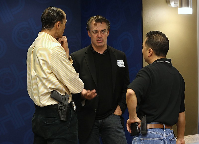 
              In this photo taken Thursday, Feb. 19, 2015,  Rick Smith, chief executive officer and founder of Taser International, center, talks with Brant Garrick left, and Kenny Park of the Vallejo Police Department who attended the Taser tech summit at the California Highway Patrol Headquarters in Sacramento, Calif.  Taser, the stun-gun maker, has become a leading supplier of body cameras for police and has cultivated financial ties to police chiefs whose departments have bought the recording devices.  A review by The Associated Press shows Taser is covering airfare and hotel stays for police chiefs who travel to speak at marketing conferences. It is also hiring some recently retired chiefs as consultants, sometimes months after their cities signed contracts with Taser.(AP Photo/Rich Pedroncelli)
            