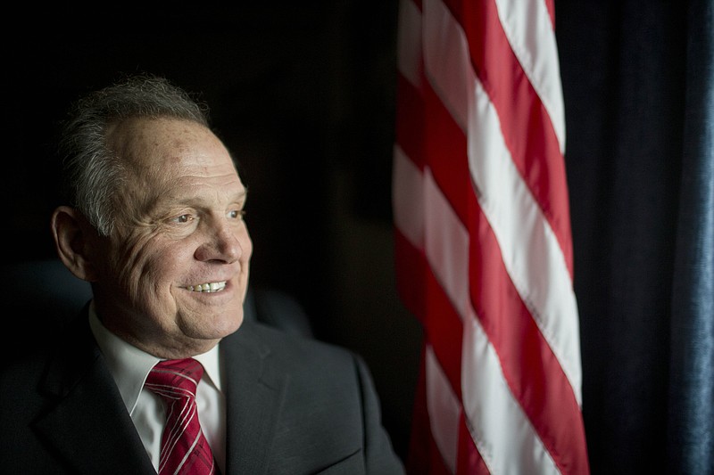 In this Feb. 17, 2015, file photo, Alabama Chief Justice Roy Moore poses in front the the American flag in Montgomery, Ala.