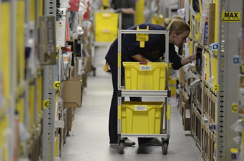 Heather Vance picks items from a row of shelves to fill orders on Cyber Monday at the Amazon Fulfillment Center in the Enterprise South Industrial Park in Chattanooga, Tenn., on Monday, December 1, 2014.