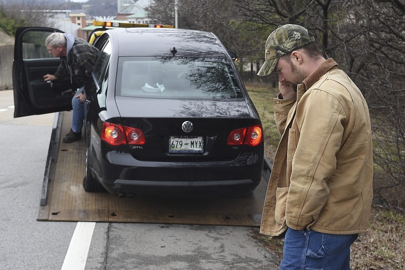 Michael McNabb talks on his phone while Cain Wrecker Company picks up his car Thursday, Mar. 5, 2015, in Chattanooga, Tenn. McNabb was headed home from his job at TVA when his car suffered two flat tires and bent wheels after hitting a pothole on Highway 27 northbound in between the MLK Boulevard exit and the Fourth Street exit. Several cars suffered flat tires before TDOT workers arrived to patch the hole. 