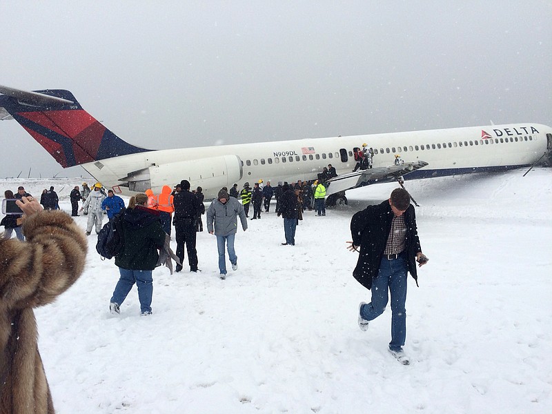 In this photo provided by passenger Amber Reid, passengers are evacuated after a Delta plane skidded off the runway while landing at LaGuardia Airport during a snowstorm Thursday, March 5, 2015, in New York.