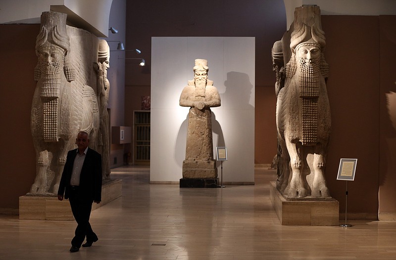A man at Iraq's National Museum in Baghdad walks past two ancient Assyrian human-headed winged bull statues in this March 1, 2015, file photo. Islamic State militants "bulldozed" the renowned archaeological site of the ancient city of Nimrud in northern Iraq on Thursday, March 5, 2015, using heavy military vehicles, the government said. 