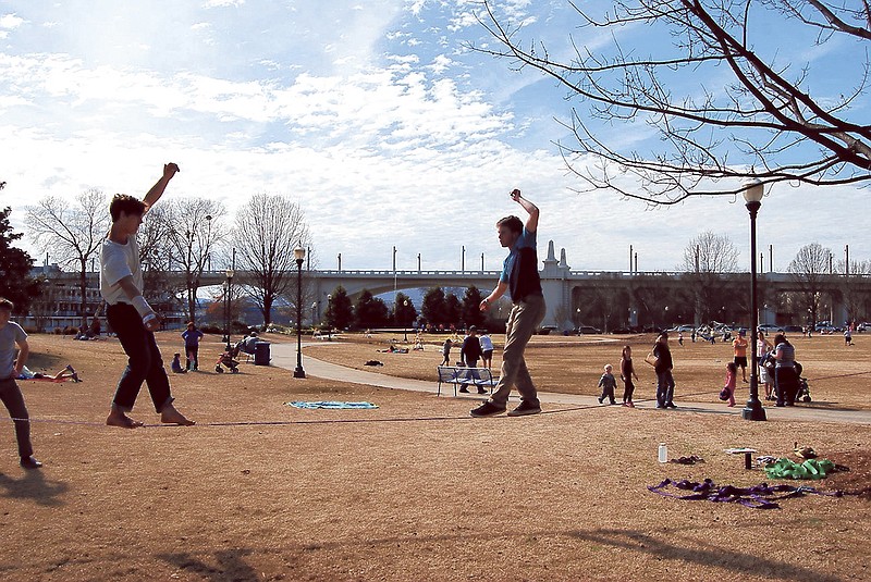 Roy Tyson, left, and Connor Peach and walk on a slackline at Coolidge Park. The teens are low-lining on 1-inch webbing 2 feet to 6 feet off the ground. High-lining, at 40 or so feet above the ground, requires a safety harness.