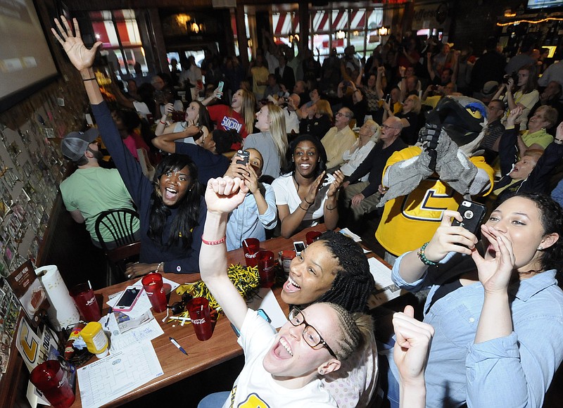 Mocs team members celebrate Monday at Jefferson's as they discover their seventh seed in the NCAA Women's Basketball Tournament in Knoxville. From bottom center clockwise are, Alicia Payne, Jasmine Joyner, Chelsey Shumpert, Ka'Vonne Towns, mascot Scrappy, Ashlyn Wert and Kayla Freeman.