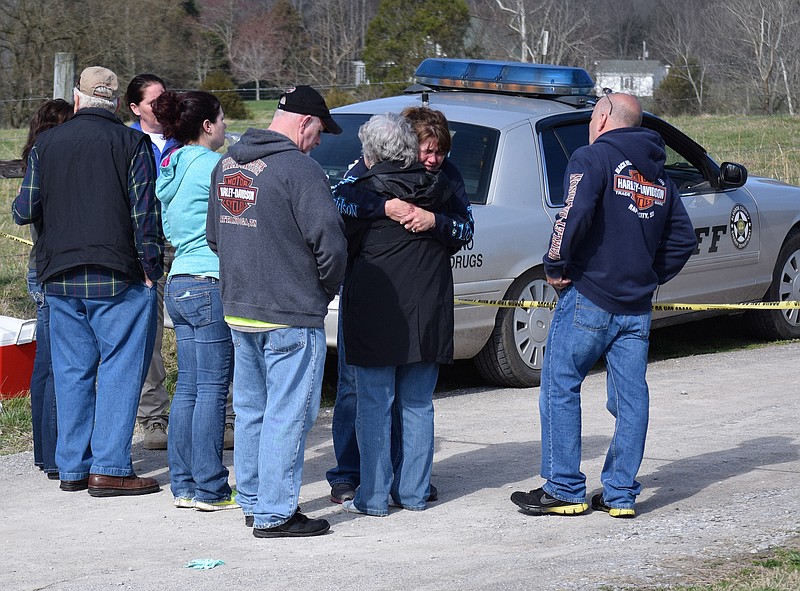 Family members and friends of Bledsoe County Sheriff's Office investigator Ricky Seals console one another at the scene north of Pikeville, Tenn., where his body was found.