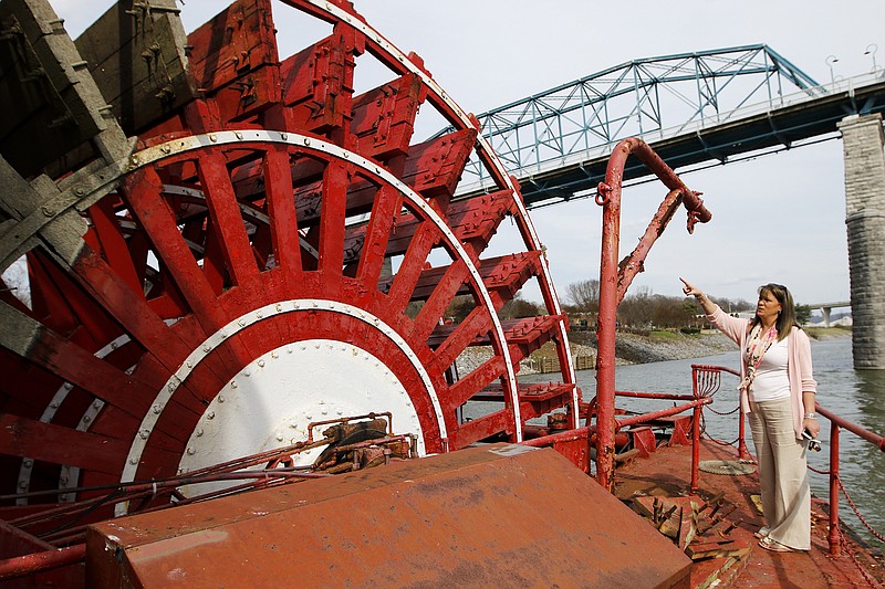 Leah Ann Ingram points to the Delta Queen's paddle wheel Tuesday at Coolidge Park. Preparations on the riverboat have been underway to prepare it for its departure on Sunday.