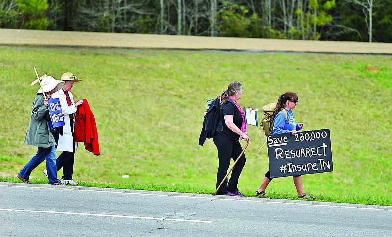 Katie Cowley-Carpenter, right, and Anna Grabowski, left, carry signs as they walk from Cleveland to Benton along Highway 64 on Wednesday, Mar. 18, 2015, in Bradley County, Tenn. They were joined by Mary Headrick, second from left, and Pamela Weston for sections of their walk, called "the journey for justice for Insure Tennessee," to draw attention to their call for more state involvement in health care.   