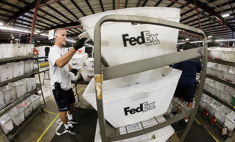 In this file photo, Mark Morrison sorts packages at the FedEx Express station in Nashville, Tenn. 