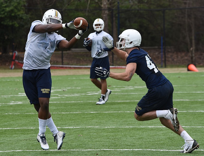 Malcolm Colvin, left, receives a pass on the first day of spring practice Friday as Kenneth Garrett defends at Scrappy Moore Field. Watching, in the background, is former Bradley standout James Stovall.