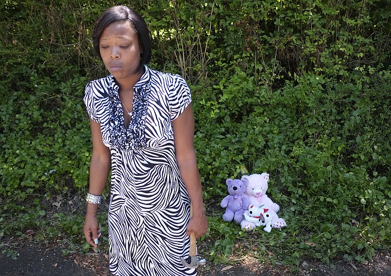 Shonda Mason stands next to teddy bears she and her daughter placed at the site where her son Eric Fluellen's body was found on 13th Avenue.
