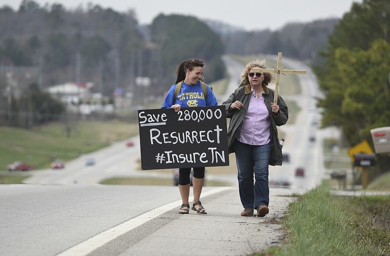 Katie Cowley-Carpenter, left, and Anna Grabowski carry signs as they walk from Cleveland to Benton along Highway 64 on Wednesday, Mar. 18, 2015, in Bradley County, Tenn. They were joined by Mary Headrick and Pamela Weston for sections of their walk, called "the journey for justice for Insure Tennessee," to draw attention to their call for more state involvement in health care.   